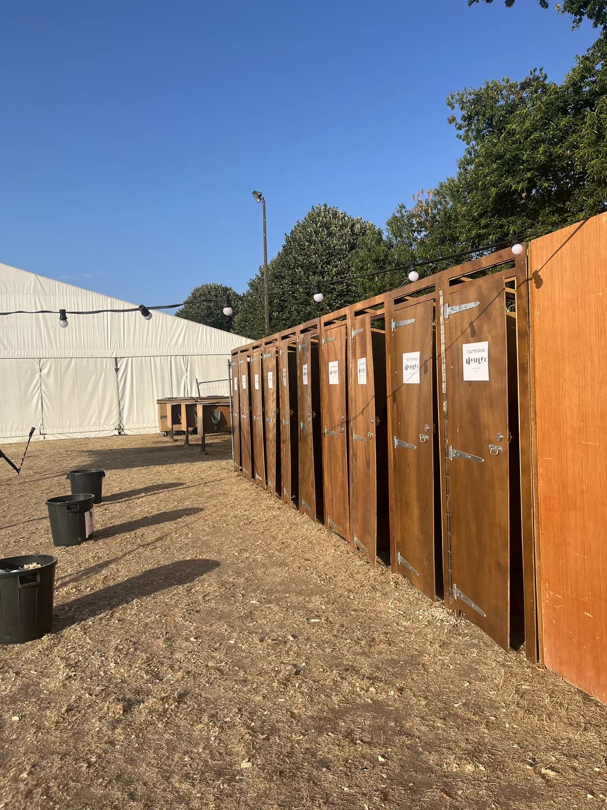 Rangée de cabines de toilettes sèches en bois aux Bandafolie’s